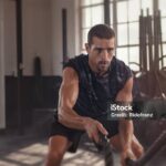 Athletic young man doing some cross training exercises with a rope. Determined fit guy doing battle ropes exercise at the cross training gym. Handsome man training with effort.